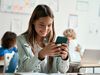 Happy Hispanic girl looking at smartphone in classroom. student, cellphone, smart phone, education, cell phone bans in school
